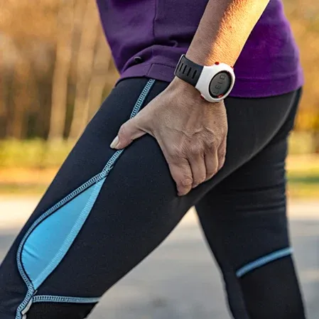 A woman in athletic clothing holding her thigh, with sciatic pain