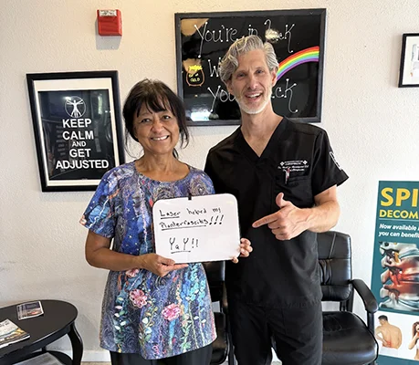 Patient and chiropractor holding a sign that reads, “Last time my medications!!! Yay!!”